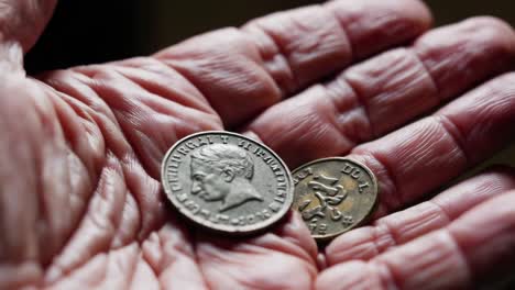 wrinkled hand of an elderly person grasping two vintage italian coins, including a 500 lire coin, stirring nostalgia for a past filled with different currency and memories