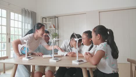 asian group of thoughtful kids study about ecology problems and their solution with wind turbine model at school. renewable energy