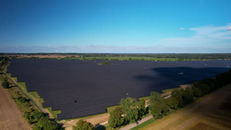 Toma-De-Drones-Que-Muestra-Una-Enorme-Granja-De-Paneles-Solares-En-El-Campo-Durante-El-Día-Soleado-Con-Un-Cielo-Azul-Claro-Al-Aire-Libre