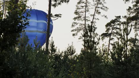 a vibrant hot air balloon floats among trees during sunset.