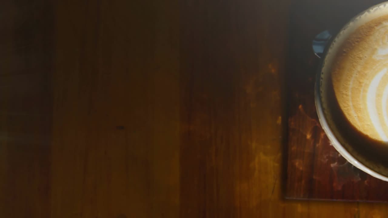 Point light emerging left, bokeh circles drifting onto latte cup lens flare illuminating leaf art