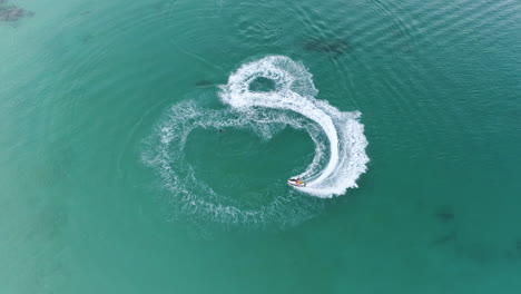 Jetskifahrer-In-Voller-Geschwindigkeit,-Der-Einen-Kreis-Und-Eine-Ausstellung-Auf-Dem-Kristallklaren-Wasser-Durchführt-Und-Eine-Spur-In-Natai-Beach,-Thailand,-Hinterlässt