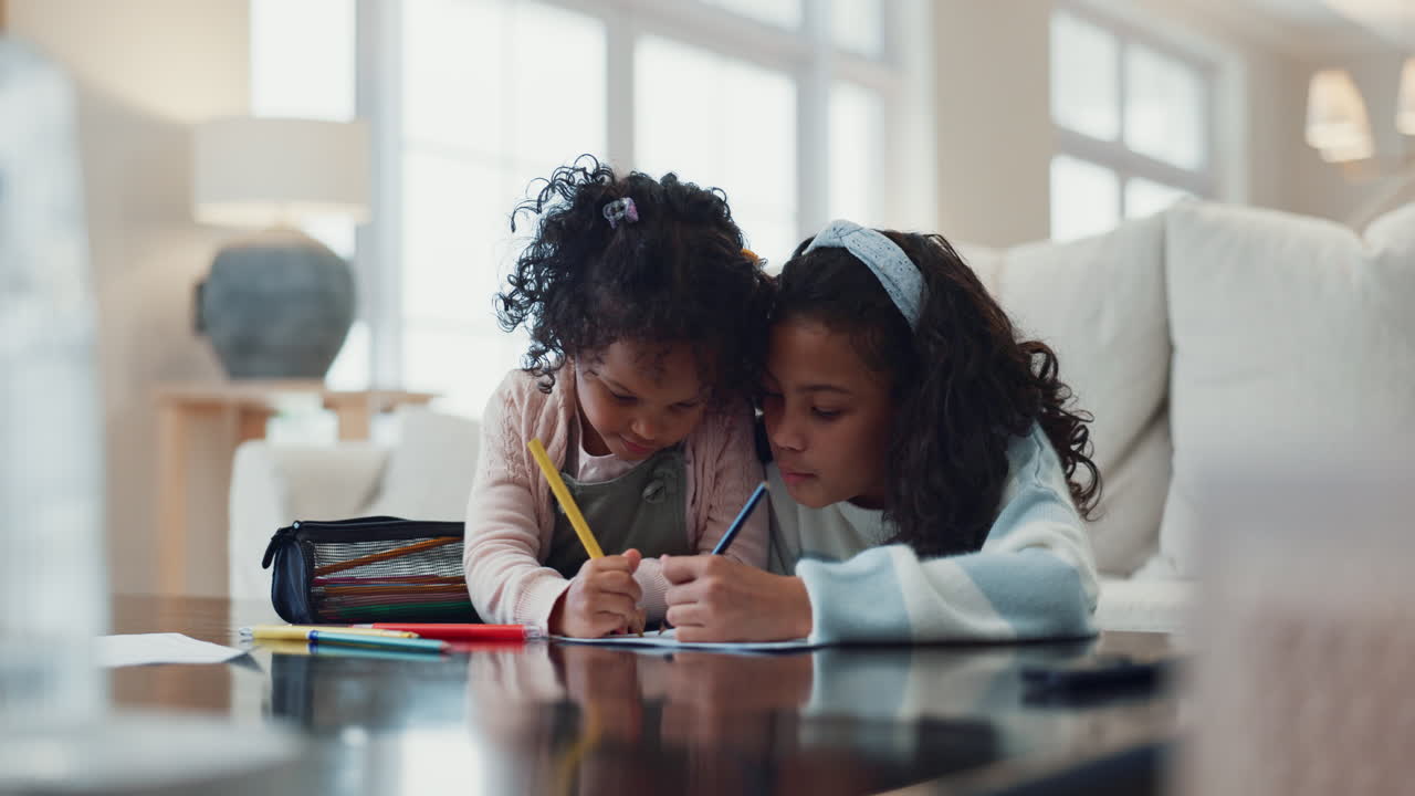 Two young sisters draw together at a table