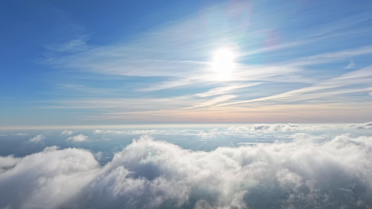 Il sole splendente illumina nuvole soffici in un cielo blu sereno, creando calma.