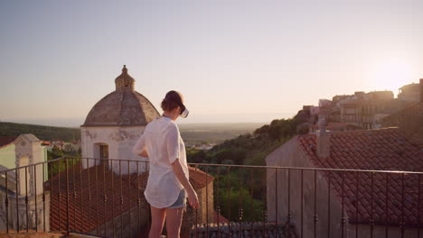 woman-using-virtual-reality-headset-on-balcony-looking-around-enjoying-experience-exploring-online-cyberspace-in-beautiful-sunset-background