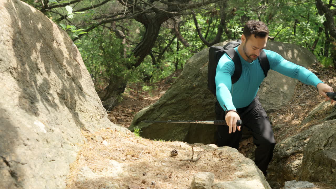 남자 하이커 는 산악 숲 의 야생 경로 에 있는 거대한 바위 에 올라간다