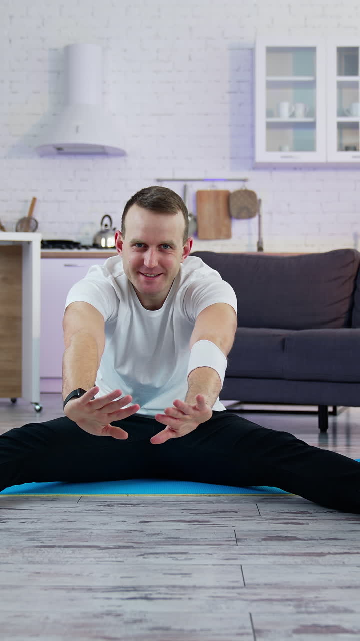 Sport exercises at home. A man does a warm-up before starting to exercise. Vertical video