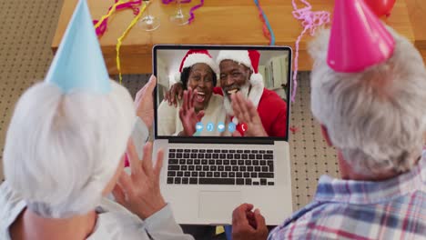 Pareja-Mayor-Caucásica-Con-Sombreros-De-Fiesta-En-Video-Chat-Portátil-Durante-La-Navidad-En-Casa