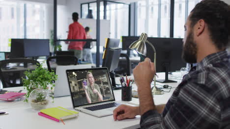 hombre de oriente medio teniendo una videollamada con una colega en una computadora portátil en la oficina