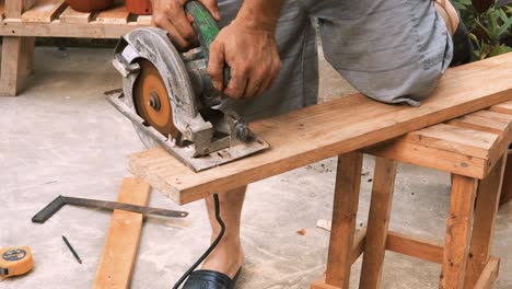 skillfull carpenter cuts with an industrial circular saw machine a piece of wood to create beautiful forniture in his outdoor traditional workshop small business