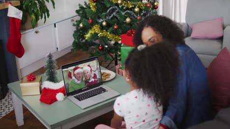 African-american-mother-and-daughter-on-video-call-with-senior-couple-at-christmas-time