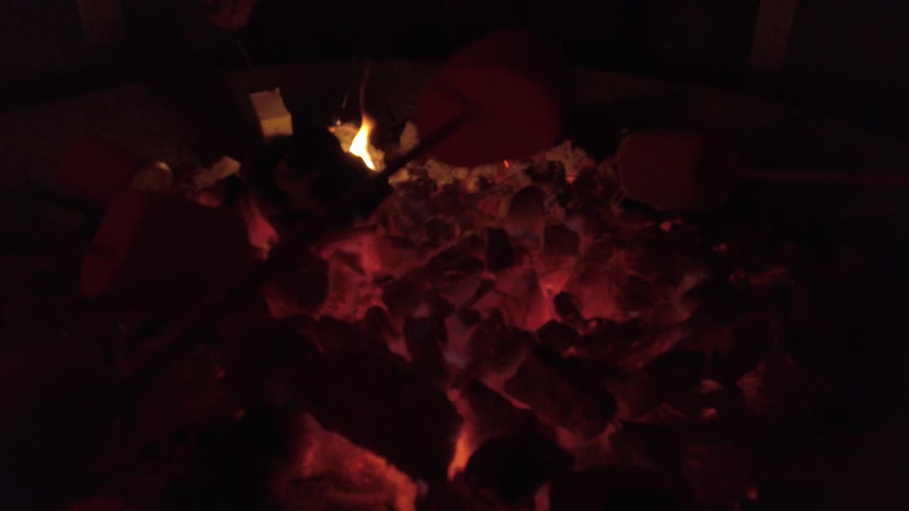 Cooking marshmellows with skewers over hot wood fire pit