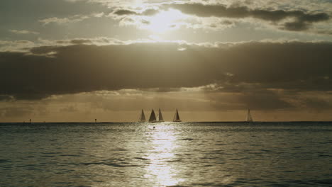 sailboats on the ocean at sunset