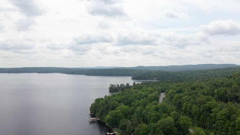 aerial footage over calm lake with thick forest along cottage country coastline. calabogie ontario