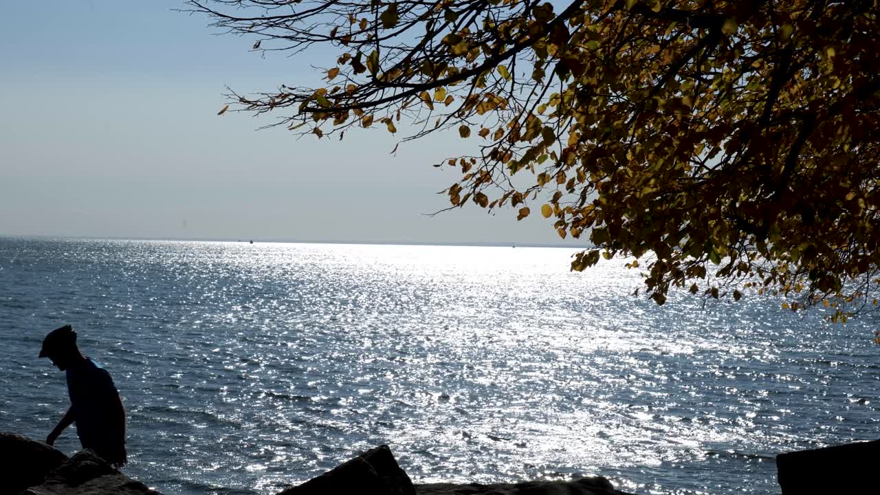 에리 호숫가를 따라 걷는 바이사이클리스트, 그들이 걷는 동안 물을 배경으로 실루엣