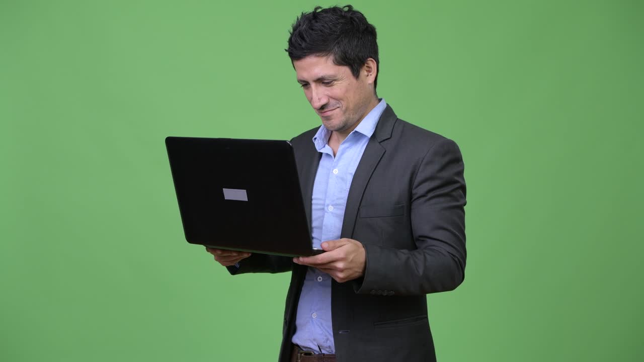 Happy Hispanic businessman using laptop
