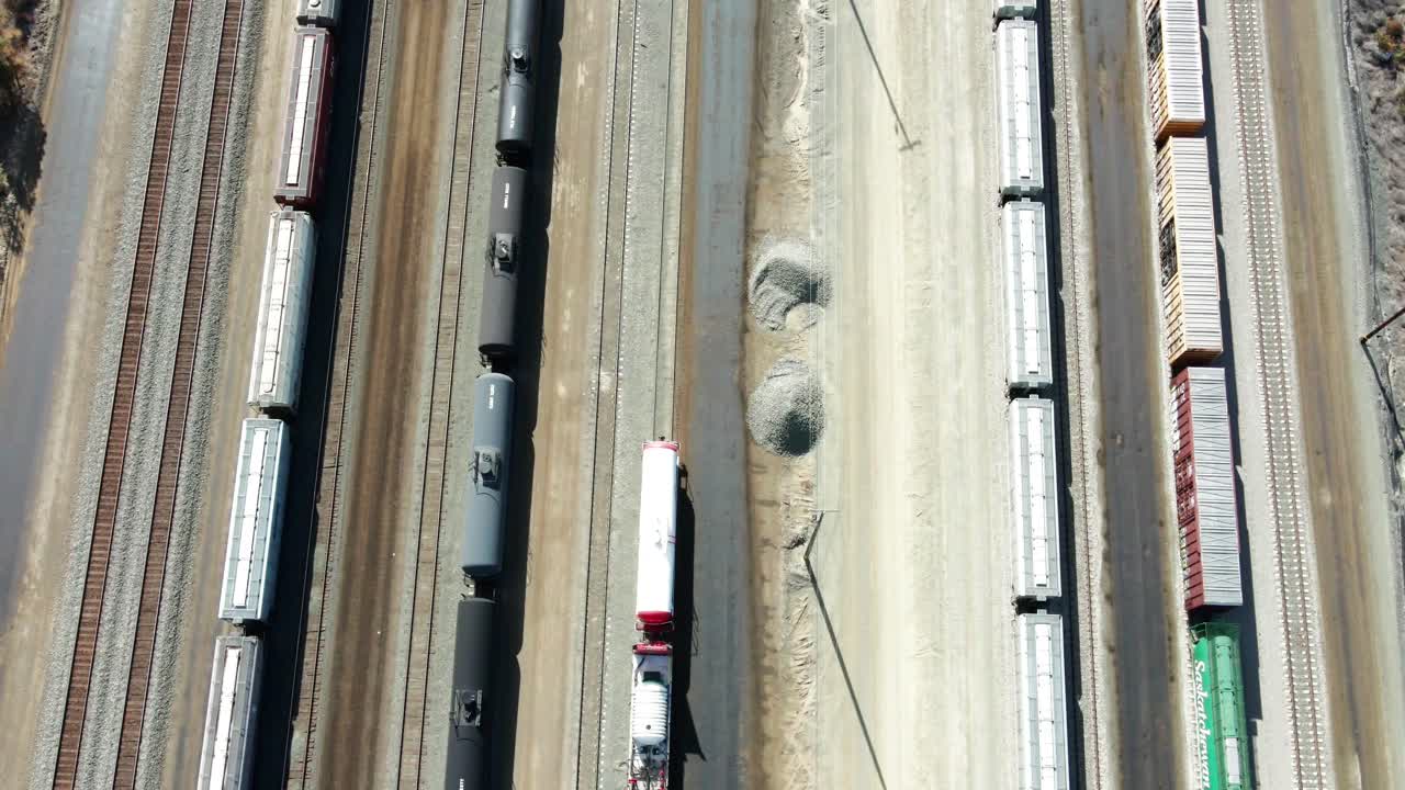 a vista de pájaro, un camión con un dron delantero disparó sobre la estación de ferrocarril en un entorno desértico en un día soleado con carga y depósito de tanques.