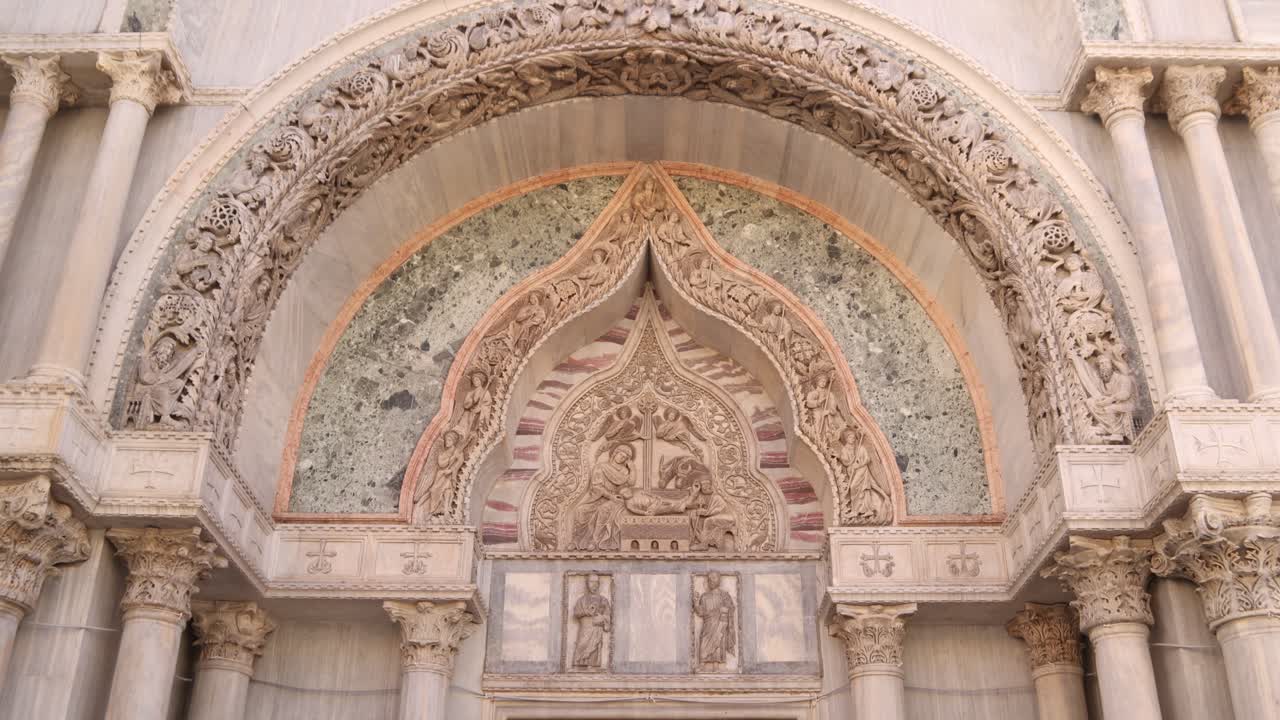 Intricate details of a Venetian church facade with ornate stone carvings and marble arches in Venice
