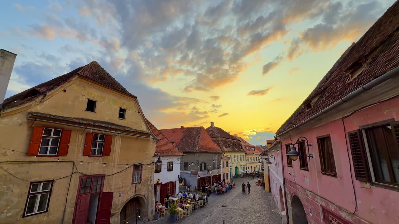 Sibiu, Romania, 17 July 2025: Historic street with restaurants at sunset in Sibiu. Old houses and cafes line a cobblestone street in Sibiu