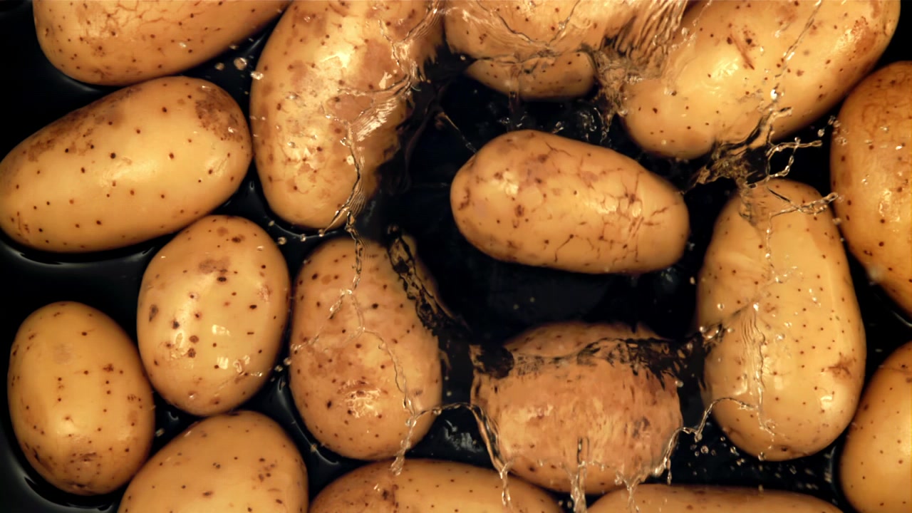 Patate crude fresche che schizzano nell'acqua, vista dall'alto