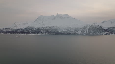 Large-boat-sails-on-coast-of-Norway-with-snowy-mountains-in-background