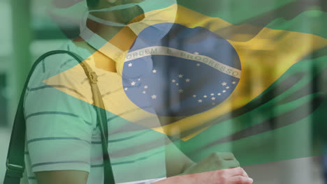 animation of flag of brazil waving over latin man wearing face mask in city street