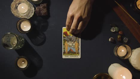 Overhead-Shot-Of-Person-Giving-Tarot-Card-Reading-Laying-Down-The-Chariot,-The-Lovers-And-The-Moon-Cards-On-Table