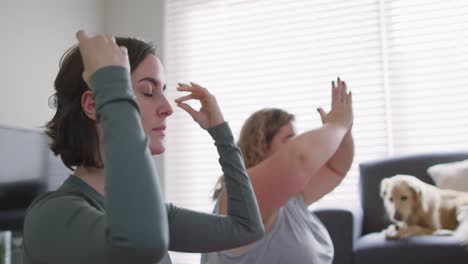 caucasian lesbian couple keeping fit and meditating on yoga mat