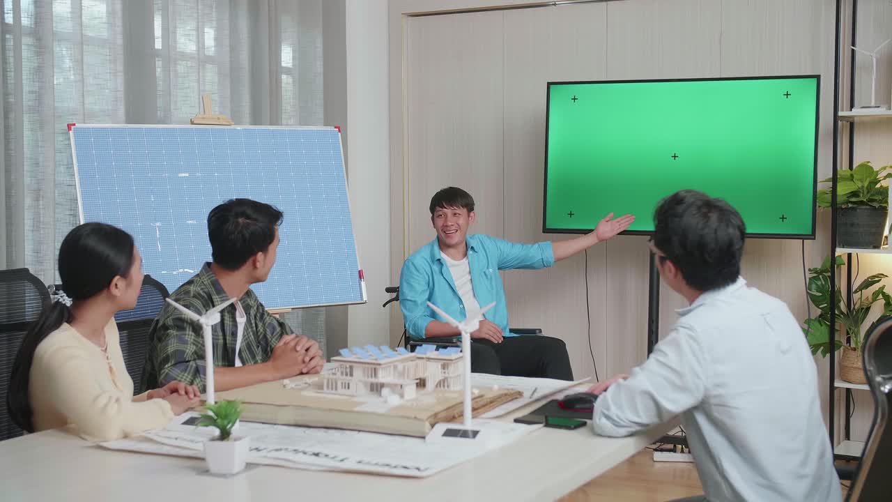 체어에 앉아 태양전지를 쓴 아시아인 엔지니어가 사무실에서 녹색 스크린 tv에 대한 프레젠테이션을 성공적으로 진행하면서 관객들은 박수를 치며 인상적이라고 느다.