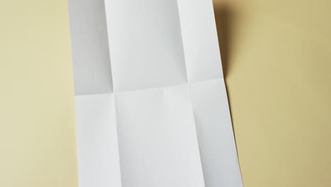 video of piece of white paper with creases on yellow background