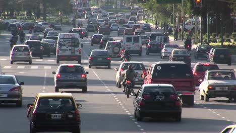 Una-Calle-De-La-Ciudad-Está-Llena-De-Autos,-Motocicletas-Y-Algunos-Peatones