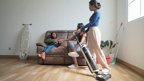 young asian mother told little daughter to help her older sister clean the house