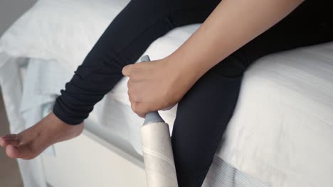 person cleaning clothes with a lint roller on a bed