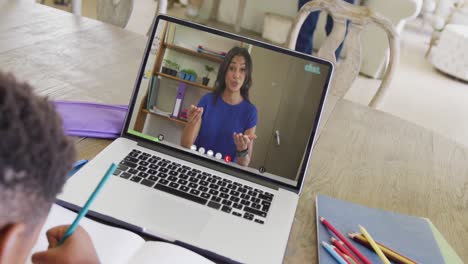 estudiante varón diverso teniendo clase durante una llamada de video portátil con una maestra en cámara lenta