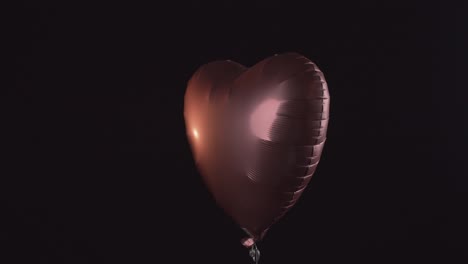 globo con forma de corazón brillante asciende aislado sobre fondo negro
