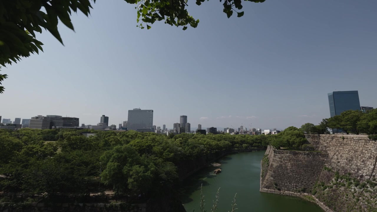 Foso alrededor del castillo de Osaka, vegetación y edificios.