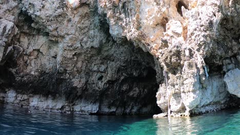 buzo nadando fuera de una cueva marina mirando hacia el impresionante acantilado rocoso que lo rodea, isla de vis, mar adriático, croacia