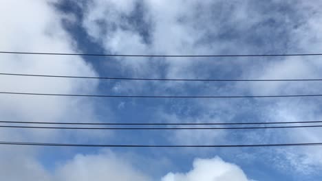 white clouds moving gently in the sky above power lines during the day in auckland new zealand