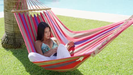 mujer soltera en bikini leyendo un libro en una hamaca