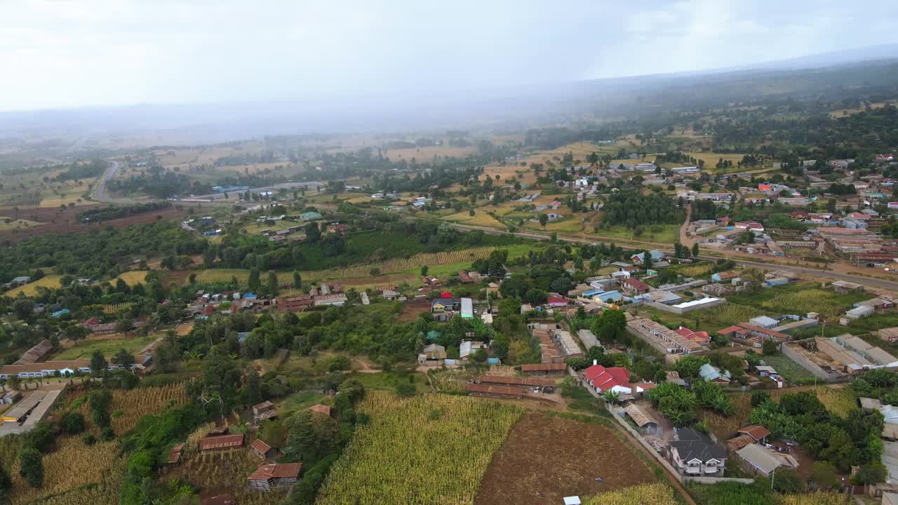 Aerial view of tropical rain pouring over a countryside village in East Africa - Descending, drone shot