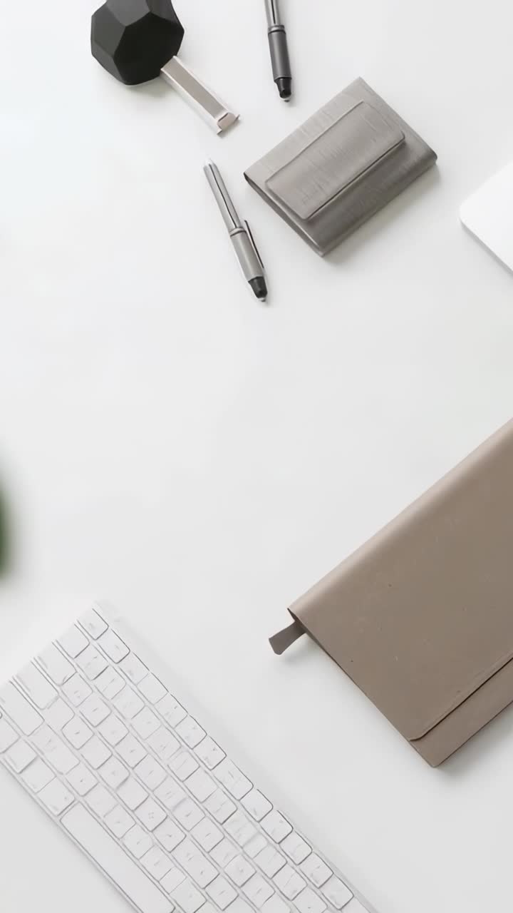 Vertical video: Tilting camera over white desk, revealing keyboard and folio to show accessories