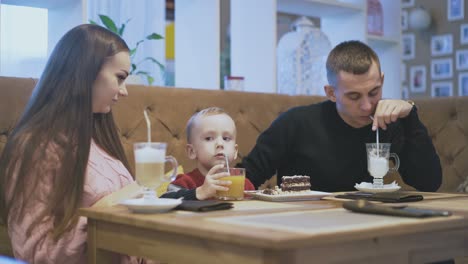 Mutter-Und-Vater-Schauen-Dem-Sohn-Zu,-Der-Orangensaft-Trinkt