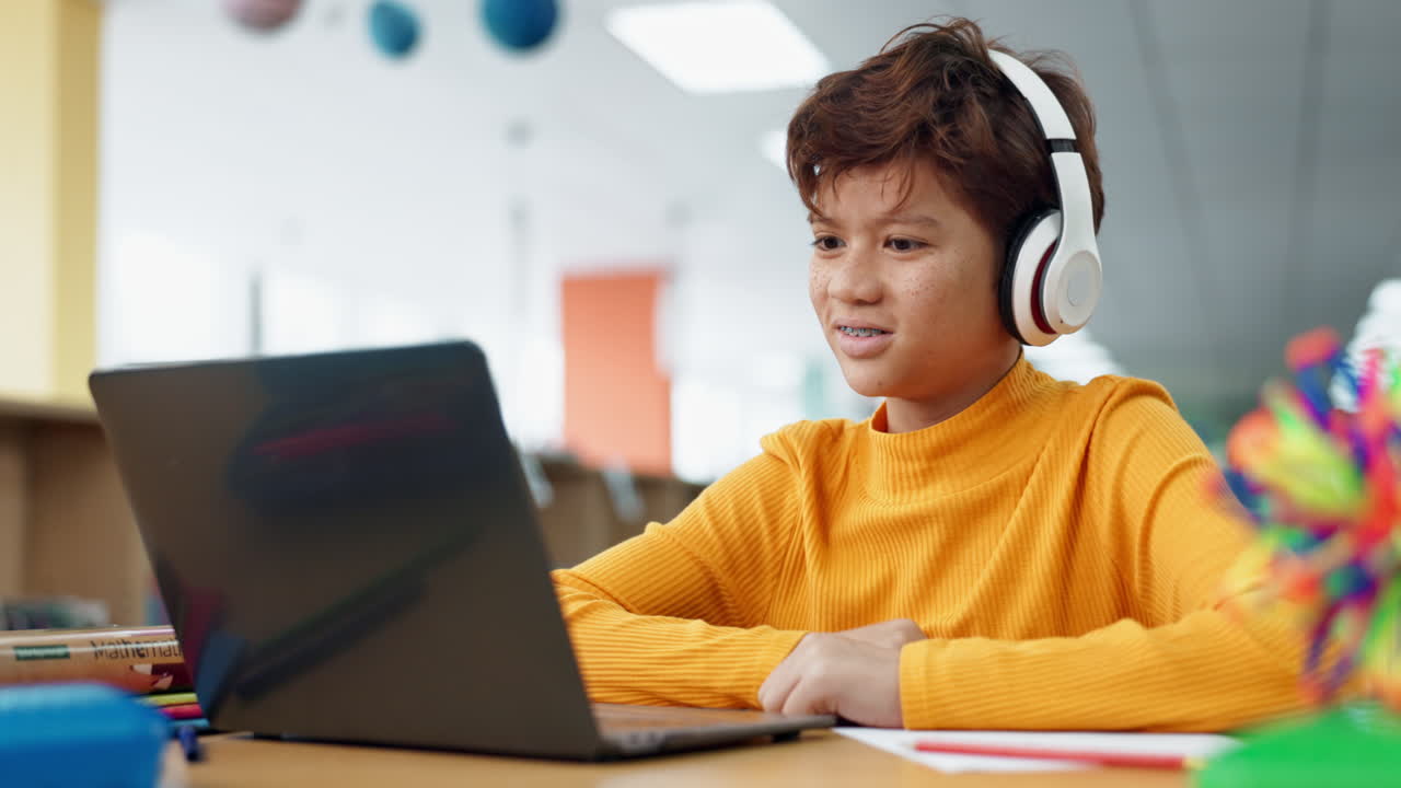 Teenage student using laptop for online learning with headphones