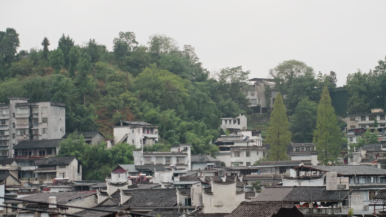 Quartiere alberghiero su una collina verde con terrazze e una chioma di alberi, luce calma e nuvolosa sui tetti tradizionali, si immaginano proprietari di boutique hotel e fotografi in visita, atmosfera di ritiro tranquillo.