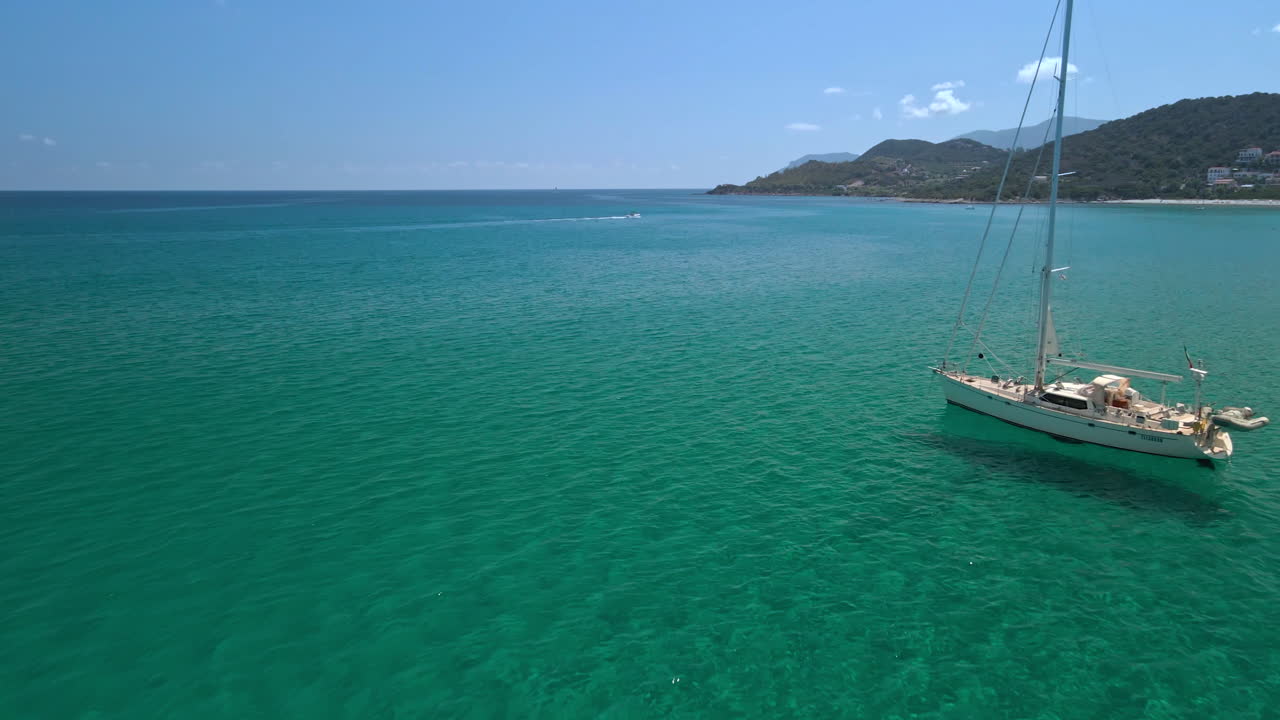 drone volador cerca del velero blanco en el mar azul tropical en la costa esmeralda en un día soleado de agosto en cerdeña, italia - tiro aéreo