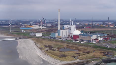 aerial view of industrial complex with power plant and wind turbines