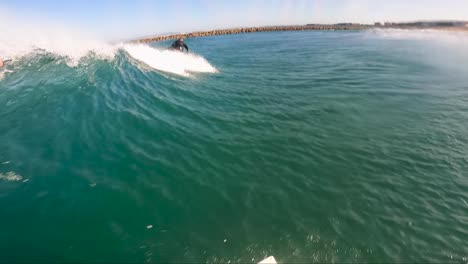 SLOW-MOTION-POV:-Surfer-paddling-and-catching-a-wave-in-crystal-clear-ocean,-other-surfer-dropping-in-front-of-him