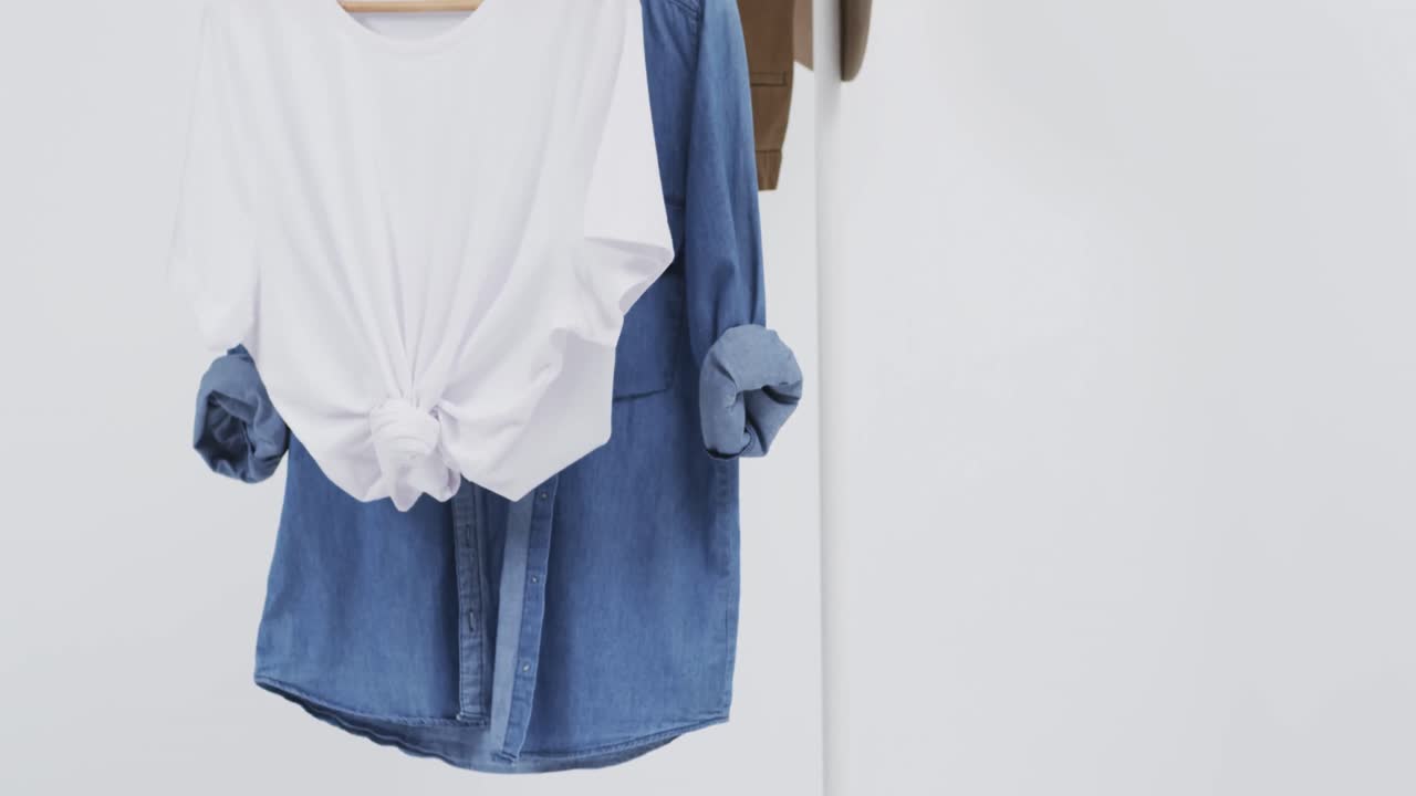video de camiseta blanca y denim en perchas, sombrero y espacio de copia sobre fondo blanco