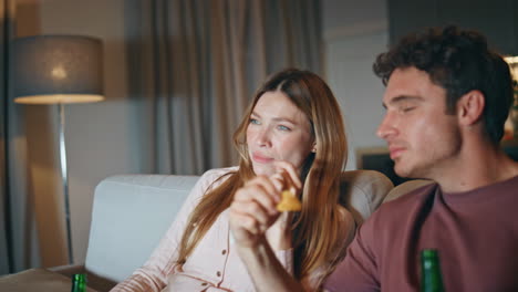 laughing couple watching sitcom sitting at night closeup. lovers eating snacks