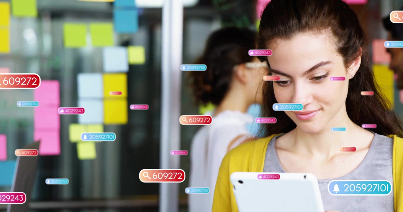 Woman tapping tablet and generating floating data tags amid sticky-note wall for business analysis
